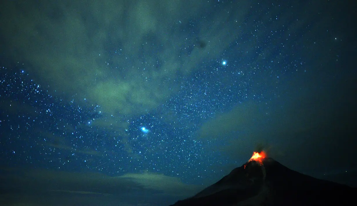 Pemandangan saat Gunung Sinabung memuntahkan lahar dan langit diterangi cahaya bintang di Karo, Sumatera Utara (28/12). Letusan yang terjadi pada Rabu (27/12) kemarin adalah letusan terbesar dalam dua tahun terakhir. (AFP/Lana Priatna)