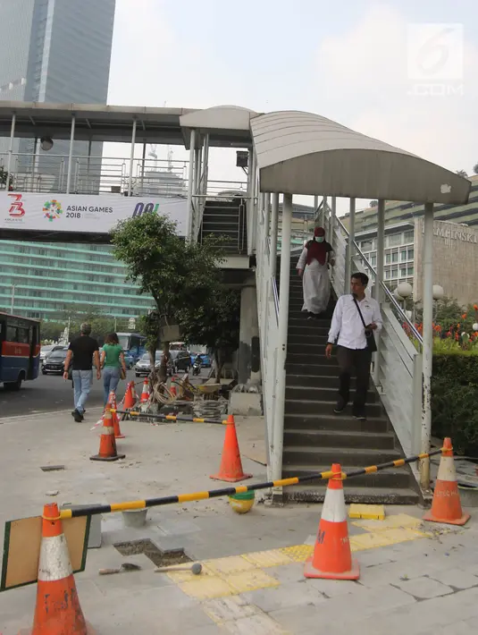 Pejalan kaki menuruni tangga jembatan penyeberangan orang (JPO) di Bundaran HI, Jakarta, Selasa (24/7). Pemprov DKI berencana merobohkan JPO tersebut karena menghalangi pandangan ke Patung Selamat Datang. (Liputan6.com/Arya Manggala)