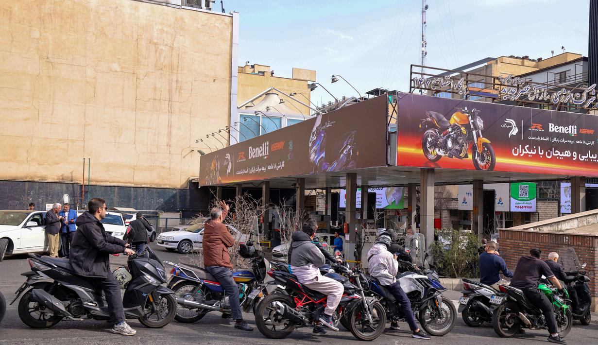 Orang-orang mengantre untuk mengisi bensin sepeda motor mereka di luar sebuah SPBU di Teheran, Iran pada Sabtu 28 Februari 2026. (Atta KENARE/AFP)