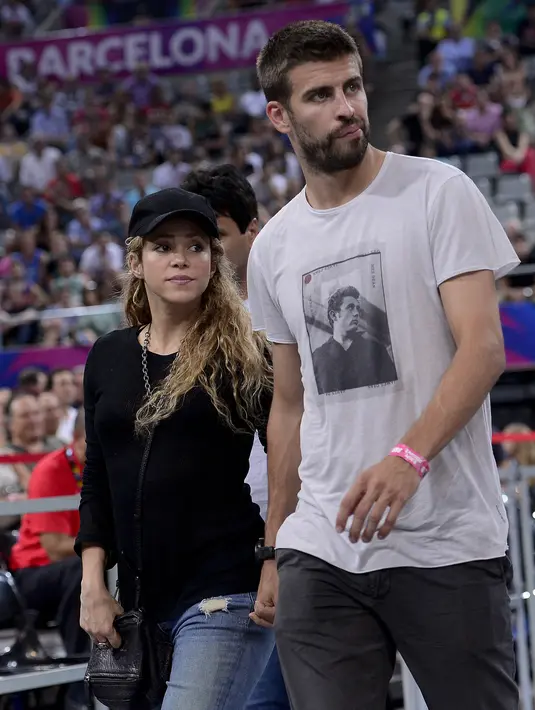 Bek FC Barcelona Gerard Pique (kanan) dan pasanganya penyanyi Kolombia Shakira menghadiri pertandingan perempat final kejuaraan bola basket Dunia FIBA ​​2014 antara Slovenia vs AS di arena Palau Sant Jordi di Barcelona pada 9 September 2014. Shakira akhirnya mengumumkan telah berpisah dari Gerard Pique pada 4 Juni 2022 usai 12 tahun bersama dan memilik dua orang anak. (JOSEP LAGO / AFP)