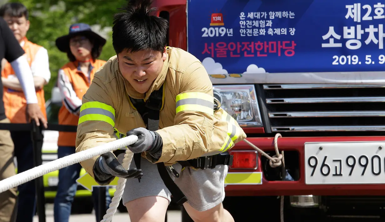 Ekspresi petugas pemadam kebakaran Lim Sung-joo saat menarik truk pemadam kebakaran dengan seutas tali dalam acara Safe Seoul Festival di Seoul, Korea Selatan, Kamis (9/5/2019). Dalam festival ini juga ada edukasi tentang pengetahuan dasar dan pelatihan CPR serta AED. (AP Photo/Ahn Young-joon)