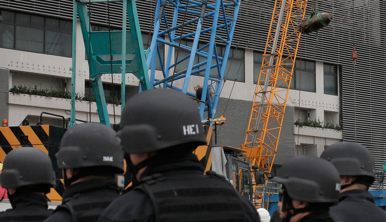 Penjinak bom dari kepolisian Hong Kong melihat proses pengangkatan bom era Perang Dunia II yang ditemukan di lokasi konstruksi di distrik Wan Chai, Kamis (1/2). Para ahli berhasil menjinakkan bom yang kondisinya sudah sedikit hancur itu. (AP/Vincent Yu)