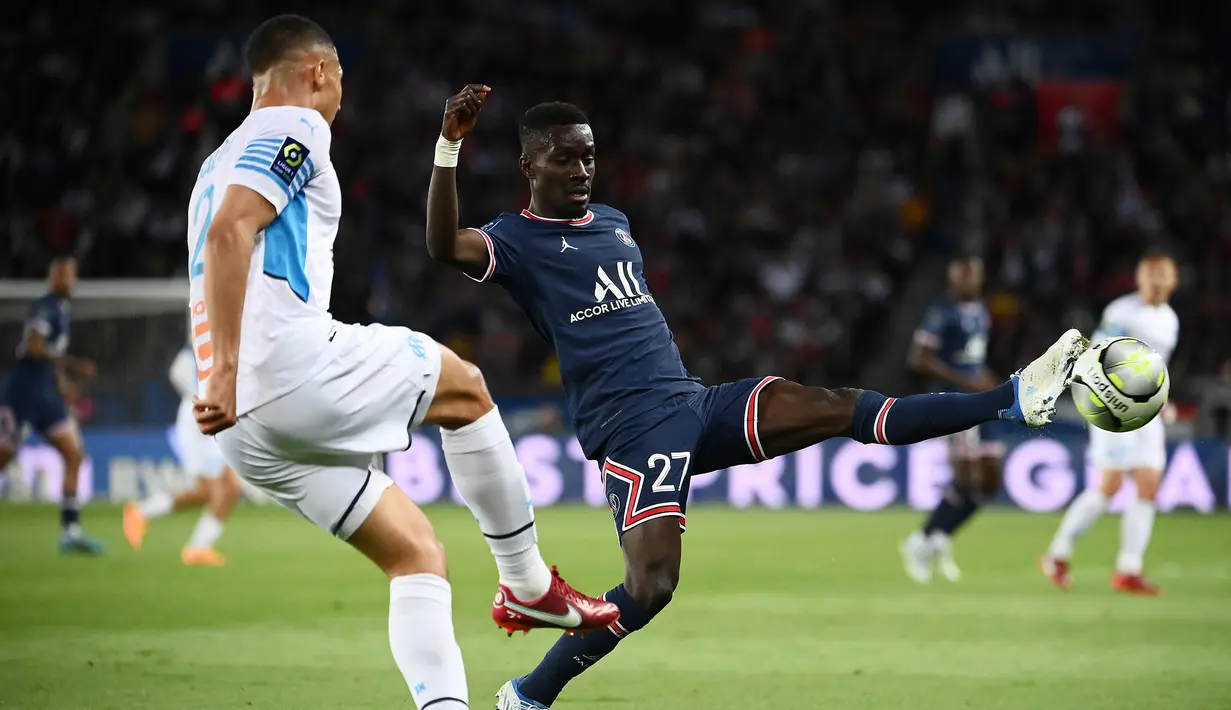 Gelandang PSG, Idrissa Gueye (kanan) berusaha memblok tendangan bek Marseille, William Saliba pada laga Liga Prancis 2021/2022 di Parc des Princes, Paris (17/4/2022). Idrissa Gueye didatangkan PSG dari AS Monaco pada awal musim 2019/2020 dengan nilai transfer 30 juta euro atau kini setara Rp505 miliar. Bertahan selama 3 musim dan total tampil dalam 111 laga dengan torehan 7 gol dan 6 assist, ia dilepas ke Everton pada awal musim 2022/2023. (AFP/Franck Fife)
