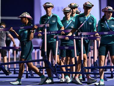 Sejumlah volunter sedang mempersiapkan lintasan cabang olahraga heptathlon 100m rintangan putri di Olimpiade Paris 2024 di Stade de France, Paris, Prancis pada 8 Agustus 2024. (AFP/Jewel Samad)