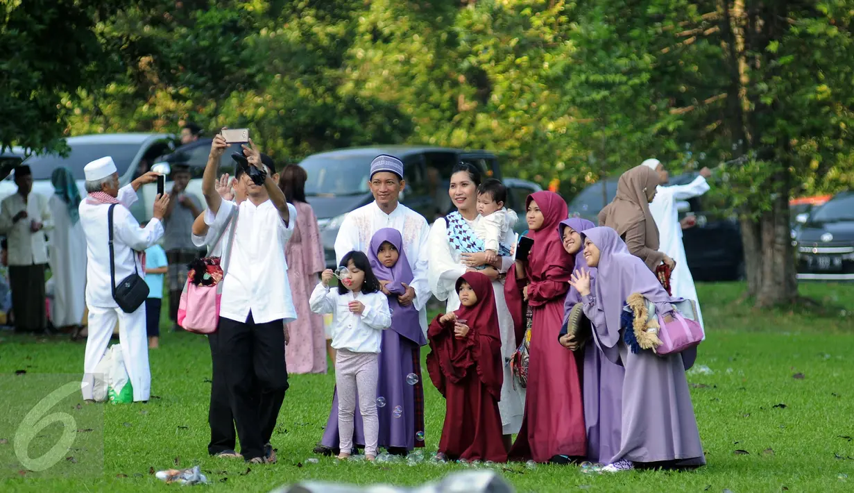 Warga berfoto keluarga secara selfie usai melaksanakan Salat Idul Fitri 1437 H di Kebun Raya Bogor, Rabu (6/7). Pemerintah Kota Bogor menyelenggarakan Salat Idul Fitri 1437 H yang dipusatkan di areal Kebun Raya. (Liputan6.com/Helmi Fithriansyah)