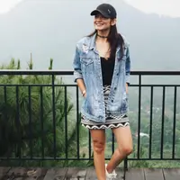 Enzy Storia tampil mengenakan oversize denim sebagai outer dipadukan inner hitam serasi dengan kalung choker yang saat itu tengah tren. Ia memadukannya dengan mini skirt hitam putih motif tribal dan mengenakan topi cap hitam.  [@enzystoria]