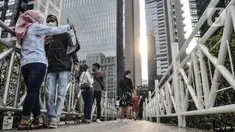 Warga berfoto di jembatan penyeberangan orang (JPO) tanpa atap di kawasan Sudirman, Jakarta, Minggu (4/4/2021). JPO tanpa atap masih menjadi wisata alternatif warga ibu kota dalam menghabiskan waktu akhir pekan untuk berfoto-foto dengan latar belakang gedung perkantoran (merdeka.com/Iqbal S Nugorho