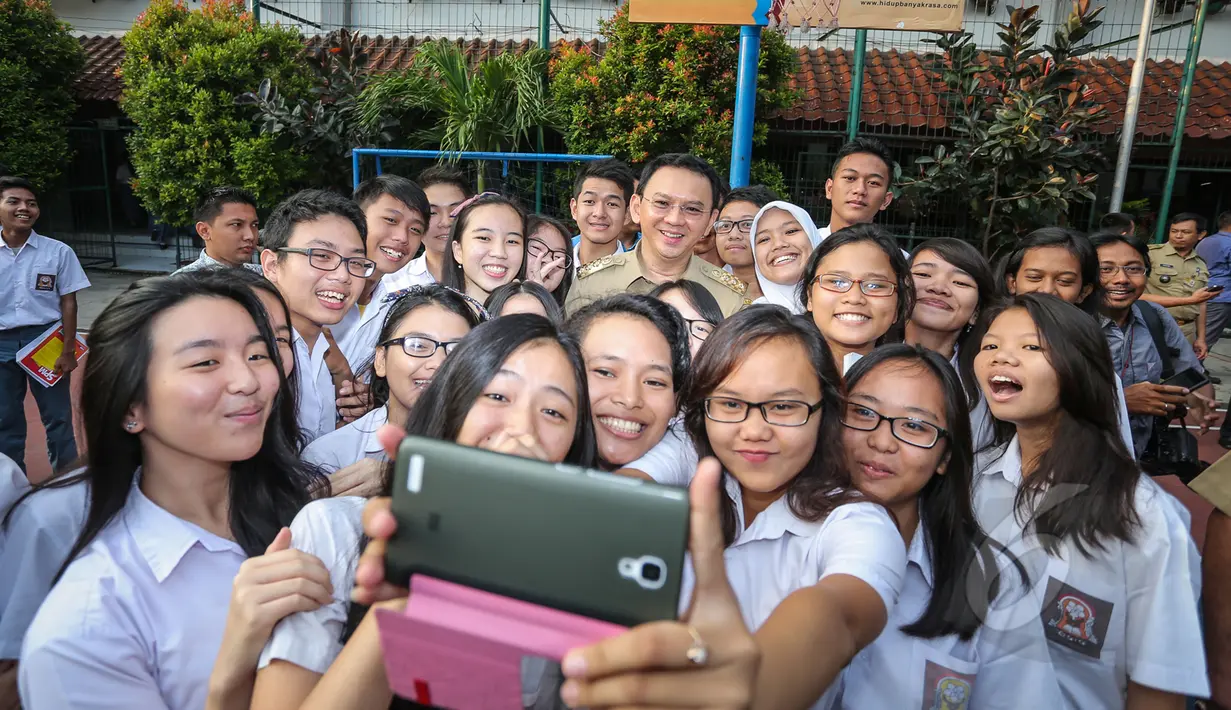 Gubernur DKI Jakarta Basuki Tjahaja Purnama (Ahok) berfoto selfie bersama para siswa SMA Negeri 2 Jakarta saat meninjau pelaksanaan Ujian Nasional (UN) di sekolah tersebut, Selasa (14/4/2015). (Liputan6.com/Faizal Fanani)