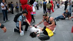 Sejumlah orang menghampiri korban terluka setelah sebuah mobil melaju kencang ke arah pejalan kaki di trotoar Times Square, New York, Kamis (18/5). Pihak berwenang menyebut tidak ada indikasi tindakan terorisme terkait kejadian itu. (Jewel SAMAD/AFP)