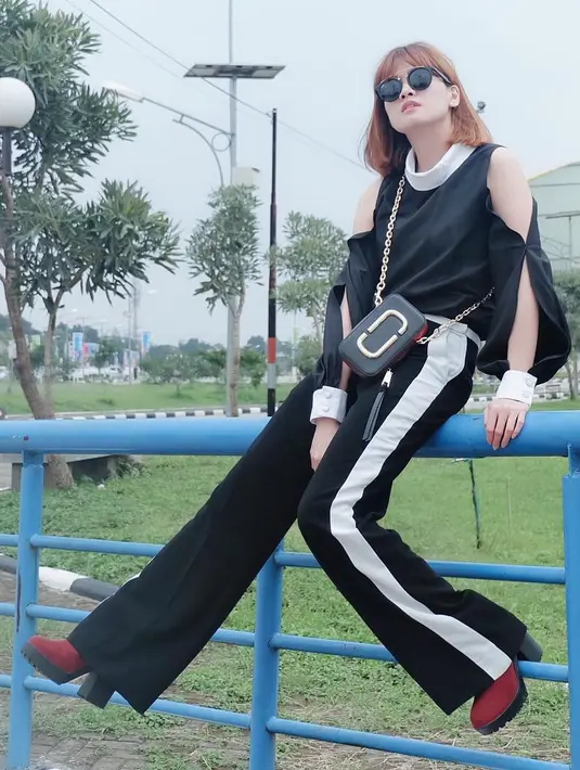 Paduan black outfit dengan wedges merah yang dipakai Chika ini sangat cocok. Gayanya kekinian banget. Terlebih dengan kacamata hitsnya itu. (Instagram/chikajessica88)