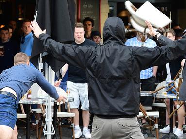 Seorang suporter Rusia melempar kursi ke arah fans Inggris saat bentrok antara kedua kubu di Lille, Prancis, Selasa (14/6/2016) atau Rabu dini hari WIB. (AFP/Leon Neal)