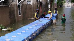 Petugas membuat jembatan apung saat banjir melanda Perumahan Periuk Damai, Tangerang, Banten, Selasa (23/2/2021). Adanya jembatan apung mempermudah warga saat melintasi banjir setinggi 2,5 meter di tempat tersebut. (Liputan6.com/Angga Yuniar)