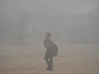 Seorang anak sekolah India melewati jalan di New Delhi yang diselimuti kabut asap, Rabu (8/11). Kabut asap tebal akibat polusi udara yang parah menyebabkan aktivitas di pusat kota New Delhi lumpuh seketika. (SAJJAD HUSSAIN/AFP)
