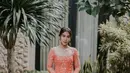 Adinda Thomas terlihat cerah di hari Lamaran dengan kebaya simple orange dari Ayung Berinda. Kebaya H-Line itu punya cross cut di bagian bawah dipadukan dengan kain Tenun keemasan [@ayungberinda]