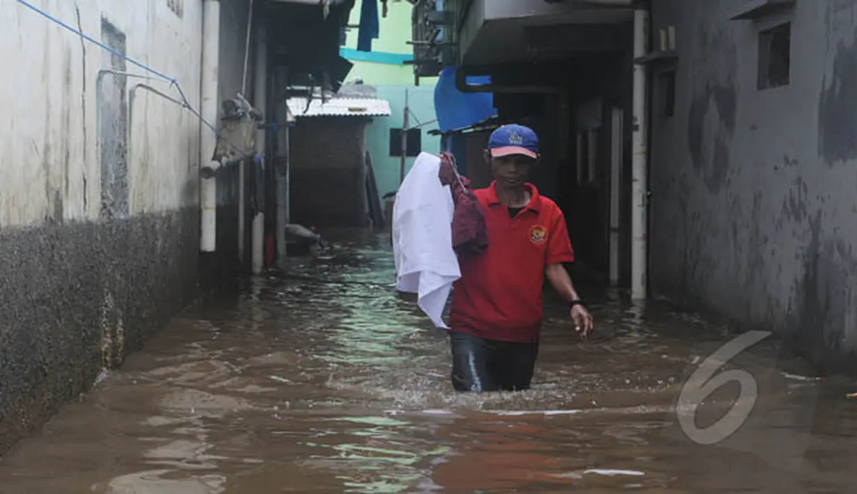 Warga melintasi banjir yang merendam Kampung Pulo, Jatinegara, Jakarta Timur, Selasa (10/2/2015). Sebagian wilayah Jakarta terendam banjir akibat hujan yang terus turun sejak Minggu (8/2) malam lalu. (Liputan6.com/Herman Zakharia)