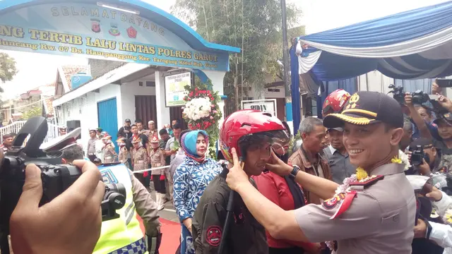 Kapolres Garut AKBP Budi Satria Wiguna, memberikan simbolis helm gratis kepada masyarakat Kampung Pasirmuncang, Garut