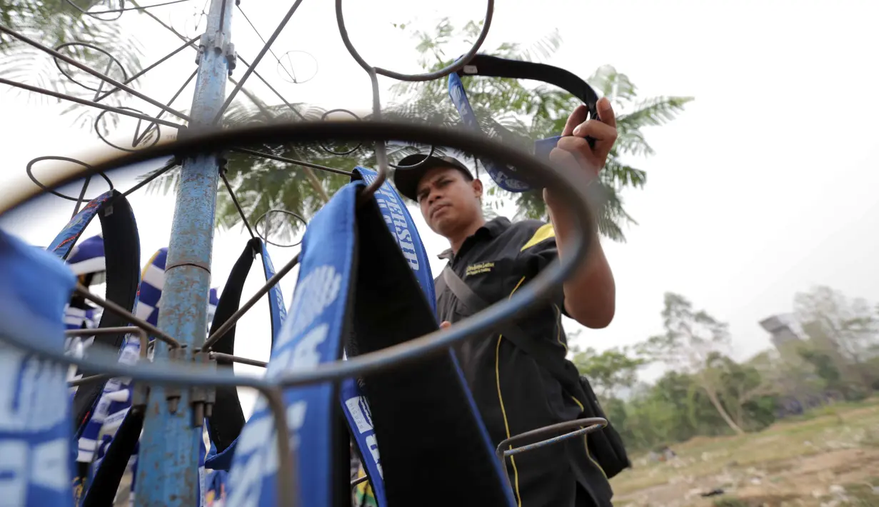 Seorang pedagang atribut merapikan dagangannya di Stadion Si Jalak Harupat, Bandung, Sabtu (24/10/2015). (Bola.com / Nicklas Hanoatubun)