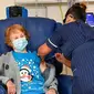 Margaret Keenan, 90 tahun, pasien pertama di Inggris yang menerima vaksin Pfizer-BioNTech COVID-19, diberikan oleh perawat May Parsons di University Hospital, Coventry, Inggris, 8 Des 2020. (Jacob King / Pool via AP)