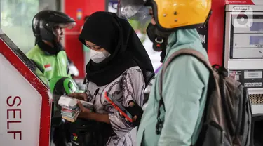 Petugas Stasiun Pengisian Bahan Bakar Umum (SPBU) mengenakan pakaian batik saat melayani konsumen di SPBU MT Haryono, Jakarta, Senin (2/10/2023). (Liputan6.com/Faizal Fanani)