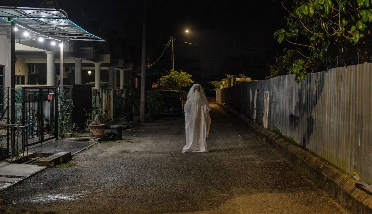 Urabil Alias, 38, mengenakan kostum hantu saat berjalan di daerah perumahan selama aturan pembatasan gerakan atau Movement Control Order di Terengganu, Malaysia, 16 April 2020. Aksi pria itu untuk menakuti warga agar tidak keluar dari rumah selama lockdown akibat virus corona. (Mohd RASFAN/AFP)