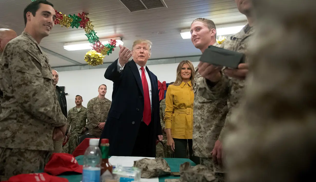 Presiden Donald Trump dan ibu negara Melania Trump menyapa pasukan militer Amerika dalam kunjungan kejutan di Pangkalan Udara al Asad, Irak, Rabu (26/12). Trump mengunjungi Irak didampingi sejumlah jajarannya selama kurang lebih 3 jam. (AP/Andrew Harnik)