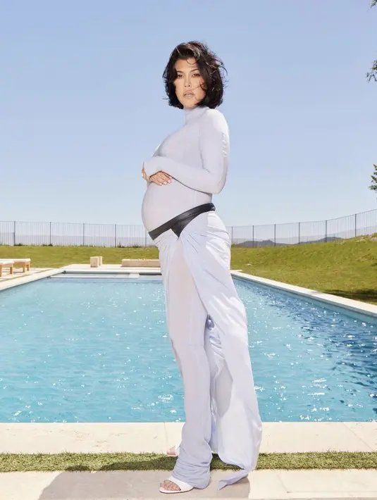 Istri Travis Barker ini tampil dengan jumpsuit ketat warna baby bump serta halter neck nya. Dipadukan sandal putihnya.  @kourtneykardash