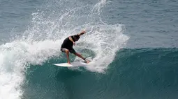 Turis beraksi di atas ombak saat bermain selancar di pantai Uluwatu Kuta Selatan di Kabupaten Badung, Bali pada 20 Desember 2018. Di Bali, terdapat banyak pantai yang merupakan lokasi ideal untuk kegiatan berselancar. (Photo by SONNY TUMBELAKA / AFP)