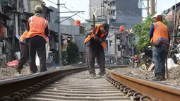 Pekerja menambahkan kerikil pada bantalan rel kereta di kawasan Roxy, Jakarta, Selasa (7/1). Penambahan kerikil tersebut dilakukan sebagai bentuk perawatan rutin agar perjalanan kereta tetap aman dan lancar. (Liputan6.com/Immanuel Antonius)