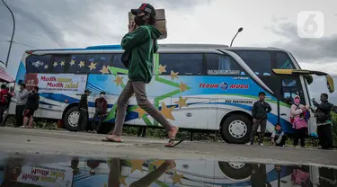 Peserta Mudik Aman Mudik Sehat Kementerian Perhubungan memanggul barang bawaan berjalan menuju bus tujuan kampung halamannya di Terminal Jatijajar, Depok, Jawa Barat, Kamis (28/4/2022). Sekitar 3.000 penumpang diberangkatkan dengan 106 bus yang telah disiapkan oleh Dirjen Darat Kementerian Perhubungan. (Liputan6.com/Faizal Fanani)