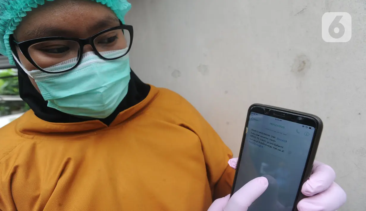 Paramedis menunjukkan SMS undangan mengikuti kegiatan vaksin Covid-19 di Puskesmas  Ciganjur, Jakarta Selatan, Kamis (7/1/2021). Kemenkes telah mengirimkan SMS blast kepada para penerima vaksin tahap pertama, terutama kepada tenaga kesehatan. (merdeka.com/Arie Basuki)