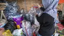 Seorang pegawai bank sampah memilah sampah anorganik rumah tangga, baik berupa karton maupun botol plastik, Jakarta, Kamis 4 Juni 2026, sebagai bagian dari instruksi Pemprov DKI yang mewajibkan warga memilih dan memilah sampah untuk mengurangi beban sampah yang semakin menumpuk di ibu kota. (BAY ISMOYO/AFP)