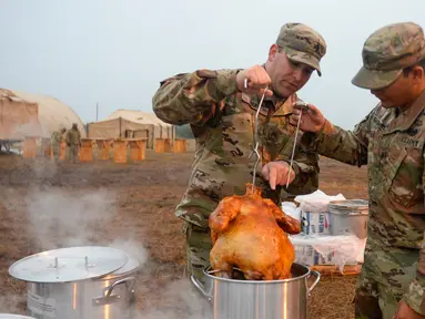 Tentara AS memasak kalkun untuk merayakan Thanksgiving di perbatasan Donna, Texas, Kamis (22/11). Para tentara sedang ditugaskan dalam Operasi Patriot Setia. (Senior Airman Alexandra Minor/U.S. Air Force/Department of Defense via AP)