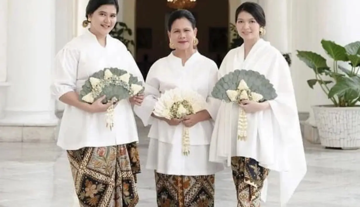 Bersama mertua dan adik ipar, ia menggenakan atasan putih dipadukam kain lilit batik sebagai bawahan.