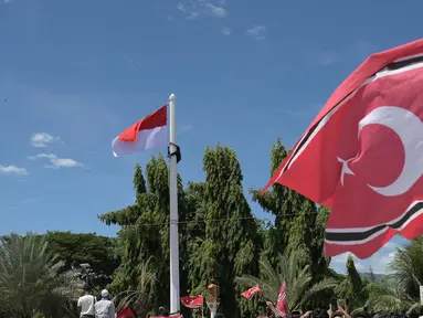 Seorang pria (kiri atas) memanjat tiang bendera saat ia berupaya mengibarkan bendera Gerakan Aceh Merdeka (GAM) bersandingan dengan bendera nasional Indonesia dalam sebuah unjuk rasa di luar Masjid Raya Baiturrahman, Banda Aceh, Provinsi Aceh, Sabtu, 15 September 2026. (AFP/ Reza Saifullah)