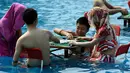 Pengunjung bermain mahjong di dalam kolam renang di wilayah Chongqing, Tiongkok, Rabu (2/8). Pemerintah setempat telah mengeluarkan peringatan merah terkait cuaca panas dengan suhu di beberapa daerah hampir mencapai 40 derajat celcius. (STR / AFP)