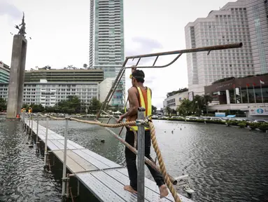 Pekerja membawa penyanggah di kolam Bundaran HI, Jakarta, Rabu (23/3). Pemasangan penyanggah bertujuan untuk menahan Tugu Selamat Datang dari getaran saat Bor Antareja proyek Mass Rapid Transit (MRT) melintas dibawahnya. (Liputan6.com/Faizal Fanani)