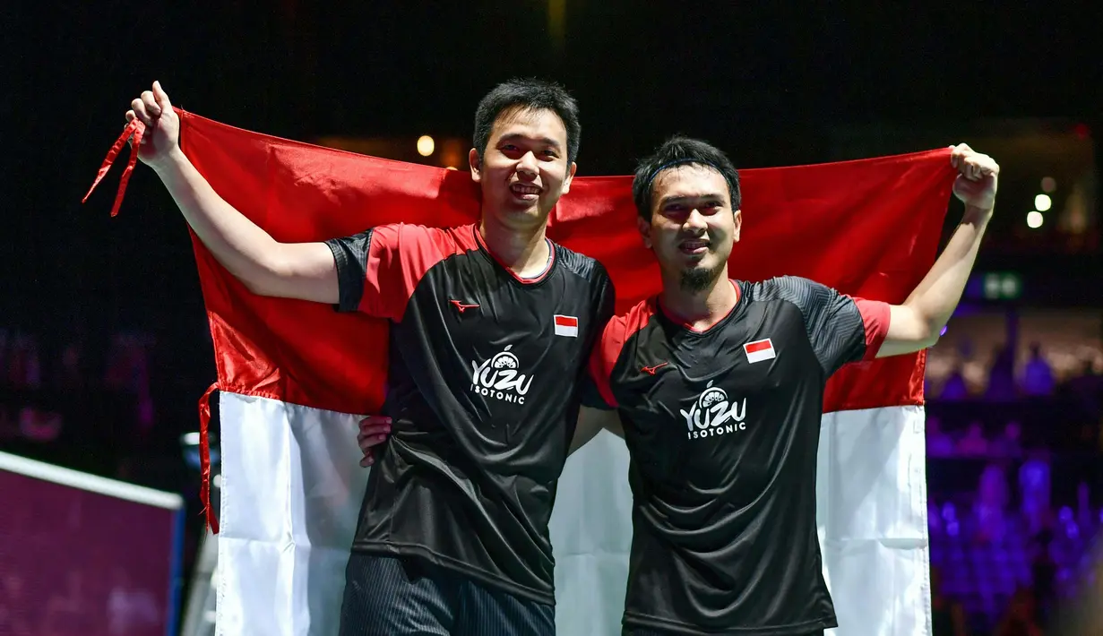 Pasangan Indonesia, Hendra Setiawan/Mohammad Ahsan melakukan selebrasi usai menjuarai Kejuaraan Dunia Bulutangkis 2019 setelah mengalahkan wakil Jepang, Takuro Hoki/Yugo Kobayashi, Minggu (25/8). Indonesia menang 25-23, 9-21, 21-15. (AFP/Fabrice Coffrini)