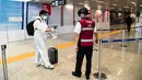 Petugas mengenakan termoscanner portabel "Smart-Helmet" untuk memeriksa suhu penumpang dan sesama staf di terminal keberangkatan bandara Fiumicino Roma, Italia pada 5 Mei 2020. Hal ini dilakukan guna menyaring orang yang memiliki gejala infeksi virus corona. (ANDREAS SOLARO/AFP)