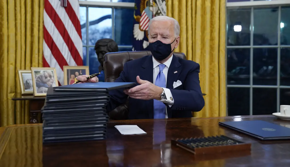 Presiden Joe Biden merapikan dokumen usai menandatangani perintah eksekutif pertamanya di Ruang Oval, Gedung Putih di Washington, Rabu (20/1/2021). Pada hari pertamanya menjabat, Presiden Amerika Serikat Joe Biden menandatangani sejumlah tindakan eksekutif di Gedung Putih. (AP Photo/Evan Vucci)