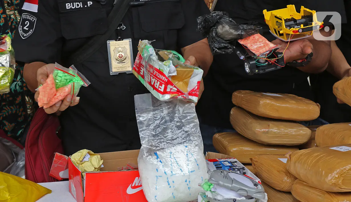 Petugas menunjukkan barang bukti dalam rilis akhir tahun di Balai Polda Metro Jaya, Jakarta, Jumat (27/12/2019). Polisi juga menampilkan barang bukti ganja dengan total mencapai 1 ton yang diamankan dari setiap polres dan wilayah hukum Polda Metro Jaya. (Liputan6.com/Herman Zakharia)