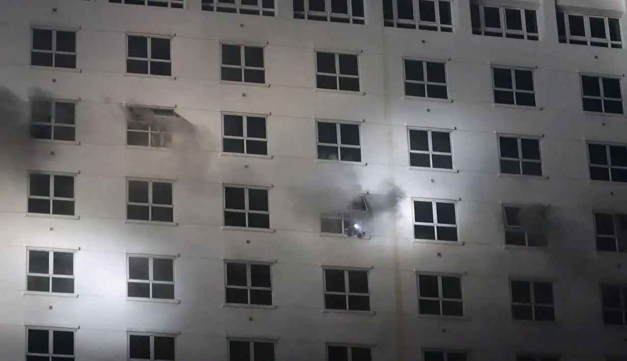 Orang-orang menyalakan lampu dari jendela di hotel-kasino Grand Diamond City saat api membakar gedung di Poipet pada 29 Desember 2022. Sebanyak 10 orang tewas dalam kebakaran di kasino-hotel Kamboja di perbatasan Thailand , dengan foto-foto yang menunjukkan kelompok-kelompok berkerumun mati-matian di tepian saat api yang ganas mengelilingi mereka. (AFP/STR)