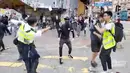Polisi (kiri) bersiap untuk menembak seorang demonstran prodemokrasi (tengah) saat terjadi protes di Distrik Sai Wan Ho, Hong Kong, Senin (11/11/2019). Polisi menembak seorang pria bertopeng saat tengah berupaya menahan seorang demonstran. (Cupid Producer via AP)