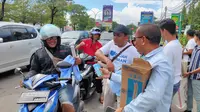 Suasana relawan Gajah Gibran membagikan susu, poster hingga kaos kepada pengendara di Cirebon. (Ist)