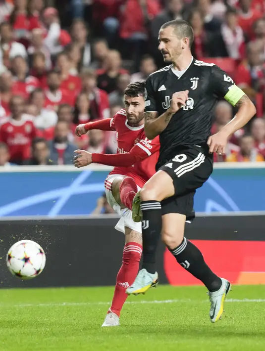 Gelandang Benfica Rafa Silva menendang bola melewati bek Juventus Leonardo Bonucci pada laga matchday 5 fase grup Liga Champions 2022/2023 di Da Luz, Rabu (26/10/2022) dini hari WIB. Berkat hasil ini, Benfica kini menempati peringkat dua klasemen Grup H dengan poin 11 dan berhak lolos ke 16 besar. (AP Photo/Armando Franca)