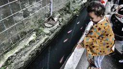 Seorang anak melihat ikan yang dipelihara di selokan di Jalan Lorong 103, Koja, Jakarta, Senin (1/3/2021). Warga setempat menyulap selokan sepanjang 100 meter tersebut menjadi kolam budi daya berbagai jenis ikan. (merdeka.com/Iqbal S. Nugroho)