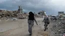 Hujan lebat dan cuaca dingin yang melanda di Jalur Gaza menyebabkan banjir dan memperumit situasi kemanusiaan bagi warga Palestina di Gaza. Tampak dalam foto, warga Palestina berjalan melewati reruntuhan di tengah cuaca buruk Kota Gaza, Kamis 11 Desember 2025. (AP Photo/Jehad Alshrafi)