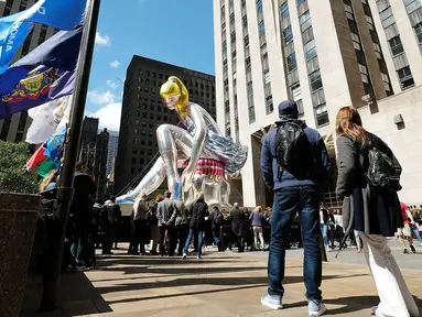 Sejumlah orang melihat balon penari balet karya seniman Jeff Koons, di Rockefeller Center, New York City, AS, Jumat (12/5). Keberadaan balon penari balet menjadi ajang foto pengunjung Rockefeller Center. (Spencer Platt / Getty Images / AFP)