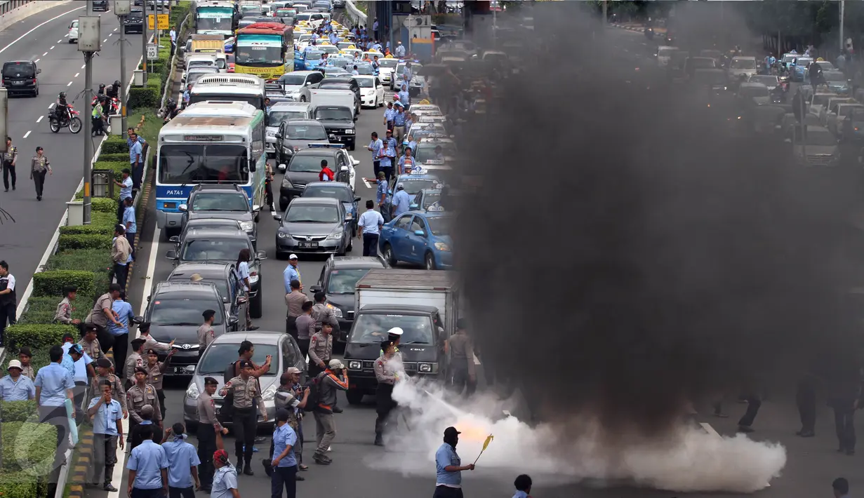 Asap hitam mengepul dari aksi bakar ban yang dilakukan sopir taksi yang melakukan demo di tol dalam kota, Mampang, Jakarta, Selasa (22/3). Para sopir taksi juga memblokade jalan sehingga kendaraan tak bisa melintas. (Liputan6.com/Johan Tallo)