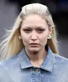 Gigi Hadid mengenakan kreasi untuk koleksi busana ready-to-wear Spring/Summer 2023 dari Givenchy yang dipresentasikan selama Paris Fashion Week di Paris pada Minggu, 2 Oktober 2022. Rambut pirang cerah milik Gigi ditata dengan cara yang sama dengan milik Bella saat ia menambahkan sepasang anting perak kecil tapi tebal. (AFP/Julien De Rosa)