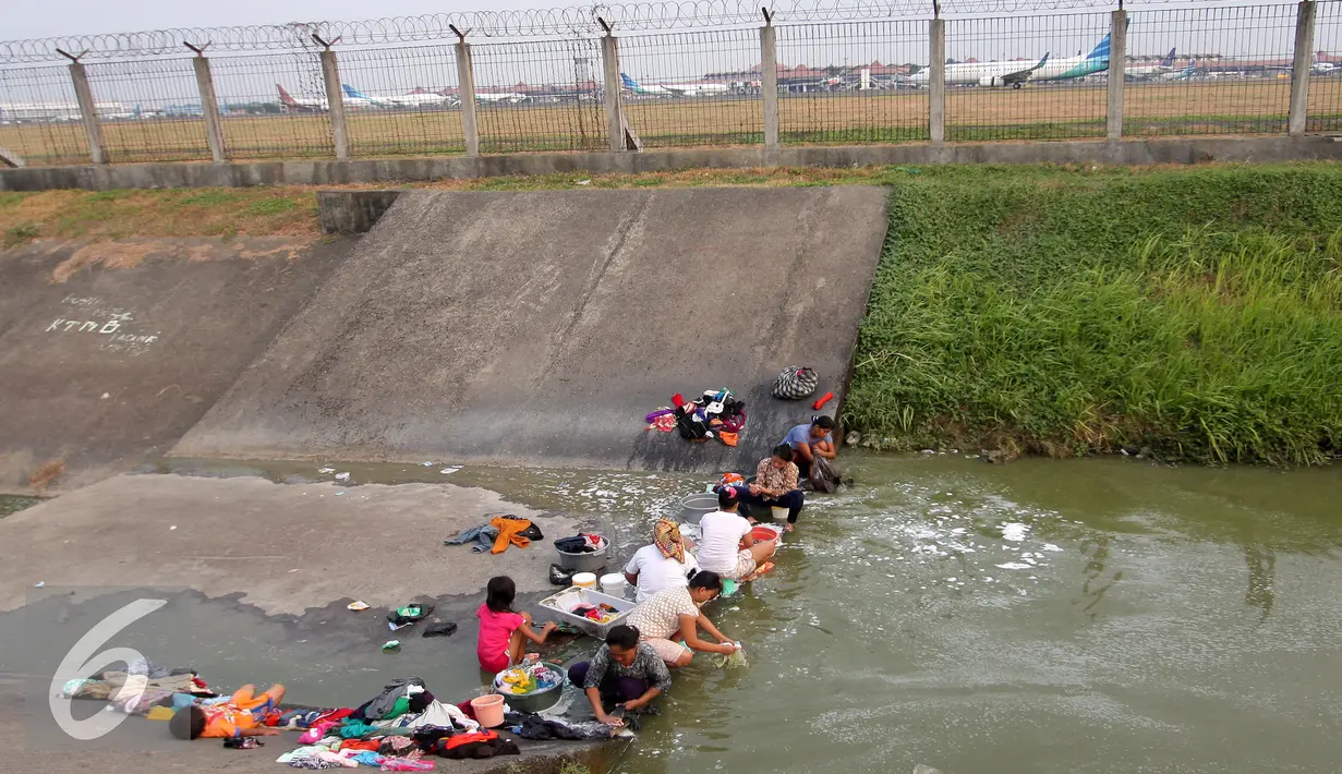 Warga mencuci pakaian di sungai yang menjadi pembatas di area Bandara Soetta, Tangerang (28/9/2015). Akibat kemarau panjang membuat pasokan air menjadi kering sehinga warga yang bermukim nekat menerobos pagar untuk mencuci. (Liputan6.com/Angga Yuniar)
